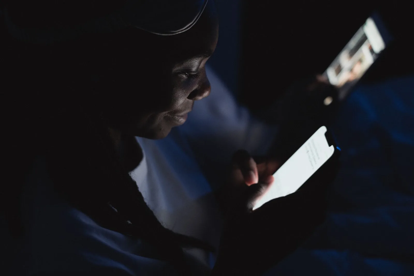 Karanlıkta telefon ekranına bakan biri